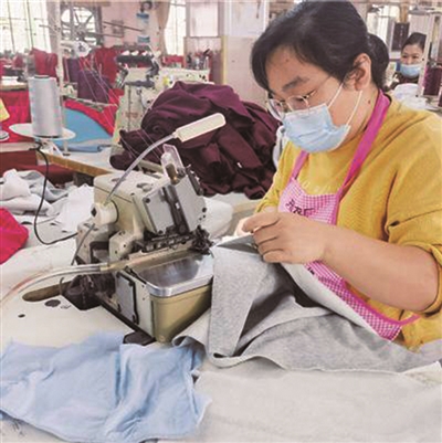 一家制衣厂的“妈妈岗”女工在缝制衣服。资料图片